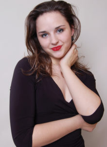 business headshot of a dancer choreographer in black dress standing with her hand under her chin