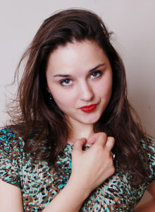 headshot of a dancer choreographer wearing a green flower dress looking at the camera