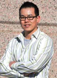 headshot of a business person in striped shirt against a wall