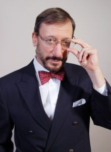 portrait of a middle aged white man with blue suit and burgundy bow tie