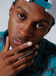 headshot of a young black model wearing a hat