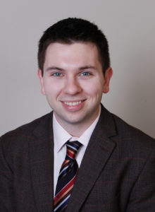 business portrait of a law student wearing a dark jacket and tie smiling