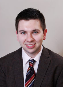 executive portrait of a law student wearing a jacket looking at the camera smiling