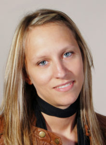 actor headshot of a woman with blonde hair wearing a brown leather jacket