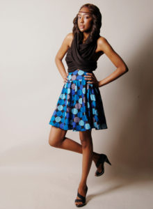 picture for model portfolio of a girl in dark wrap-around blouse and blue dotted skirt her hands on her hips