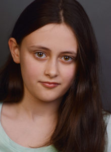 headshot of a child actress in dc leaning her head looking at the camera