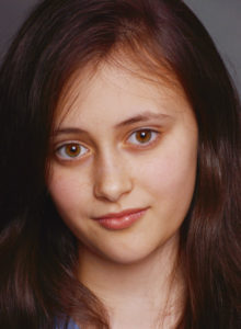 headshot of a child actress in dc looking at the camera with head tilted and a hint of a smile