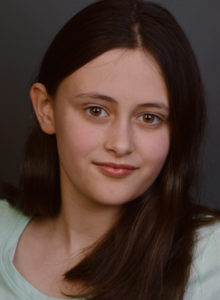 headshot of a child actress in dc leaning her head with a smile