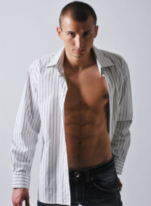 picture of a male model with faded jeans and unbuttoned shirt in dramatic lighting