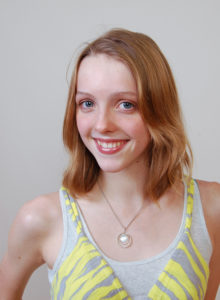 headshot of a teen model wearing a yellow striped tank top smiling