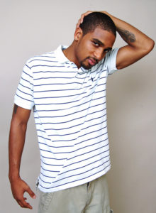 picture of a black male model in striped shirt standing with a hand on his head