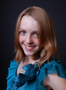 headshot of a teen model with blonde hair and green blouse 