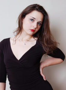 headshot of a dancer with black dress resting her hand on her hip