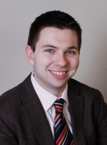 business headshot of a young man in suit smiling