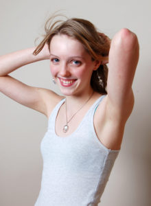 headshot of a teen model in tank top lifting her arms