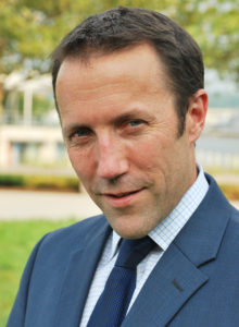 casual business headshot of a man in suit leaning his head looking at the camera