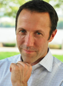 casual business headshot of a man with chin resting on his hand