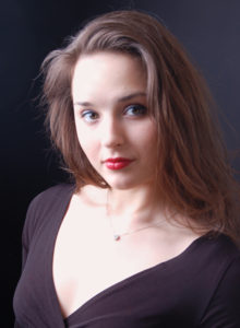 headshot of a dancer choreographer in soft focus looking at the camera with a muted smile