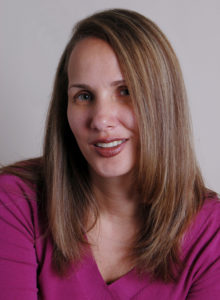 headshot of a female news reporter leaning her head looking at the camera with a smile