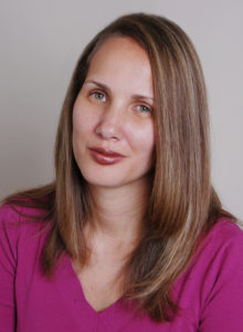 headshot of a female news reporter with dark red lipstick leaning her head looking at the camera