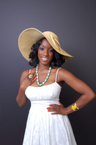 picture of a promotional model wearing a white lace dress and large brim hat and accessories smiling