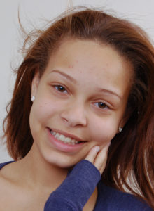 headshot of a teen actress in dc in a long sleeve blue t-shirt and a youthful smile
