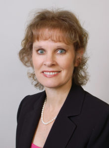 headshot of a healthcare professional in a dark suit and pink blouse smiling