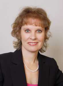 professional headshot of a woman in a dark jacket and pink blouse