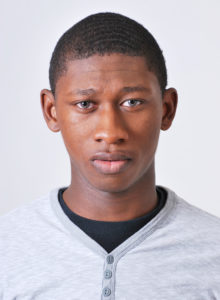actor head shot of a black teen actor wearing a light blue shirt with a straight look