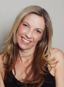 author headshot of a female freelance writer in black dress with her head tilted smiling