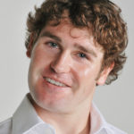 headshot of a young actor with white shirt leaning his head playfully
