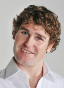 headshot of a young actor with white shirt leaning his head playfully