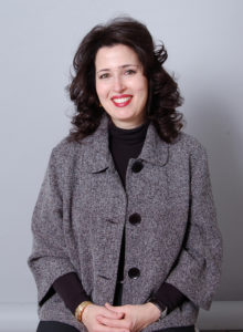 headshot of an interior designer in dark grey jacket and black sweater for promotional use