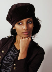 headshot of a model in casual military jacket wearing a hat