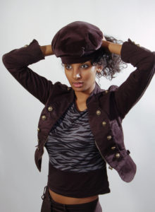 edgy pose of a model with curly hair in military jacket and a hat